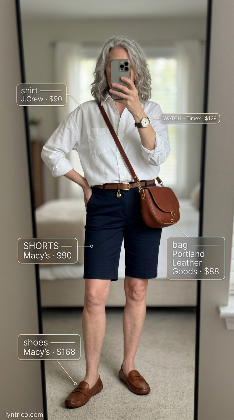 Breezy summer outfit for women over 60 2026: Navy Bermuda shorts, white shirt, loafers, and crossbody bag.