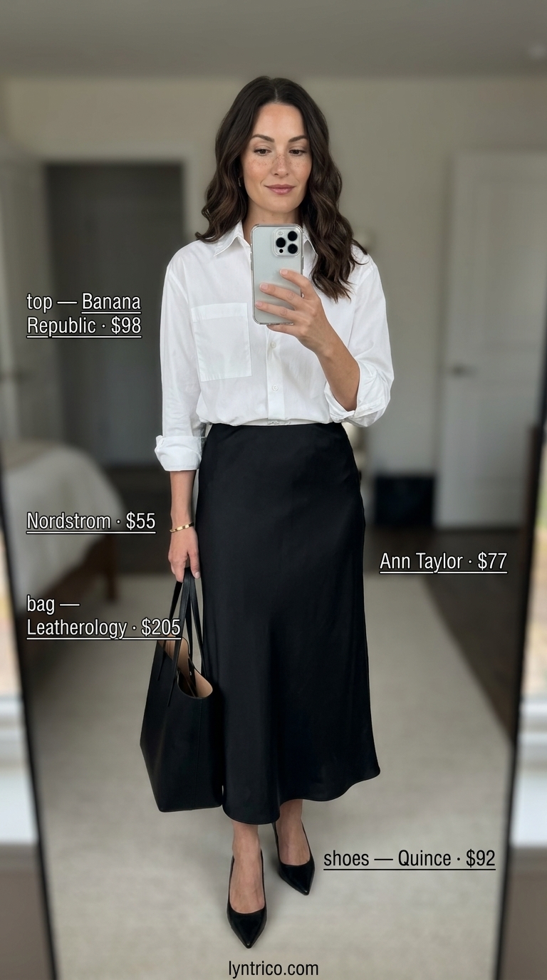 Flattering summer outfit for women over 40 2026: Black satin midi skirt with white oversized shirt and pumps.