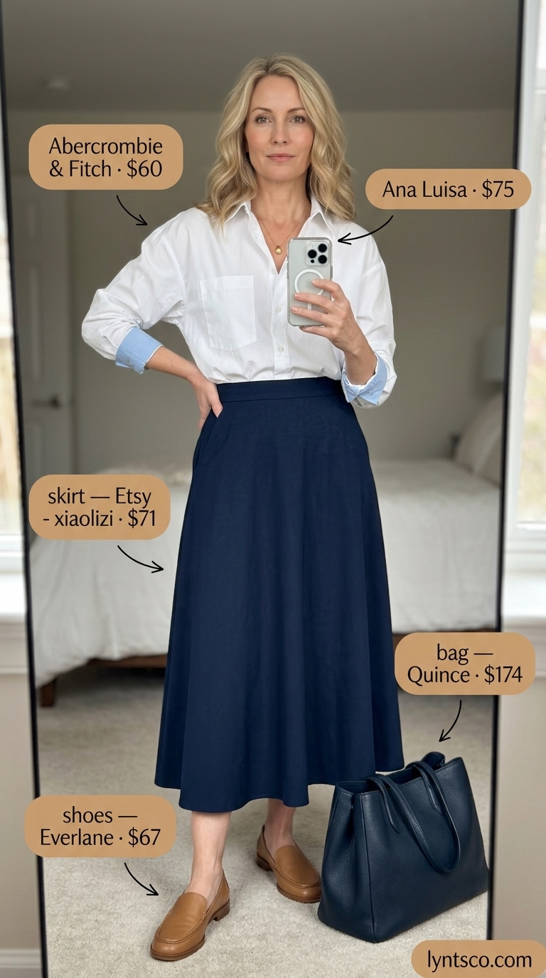 Timeless summer outfit for women over 50 2026: White button-down, navy midi skirt, tan loafers, leather tote.