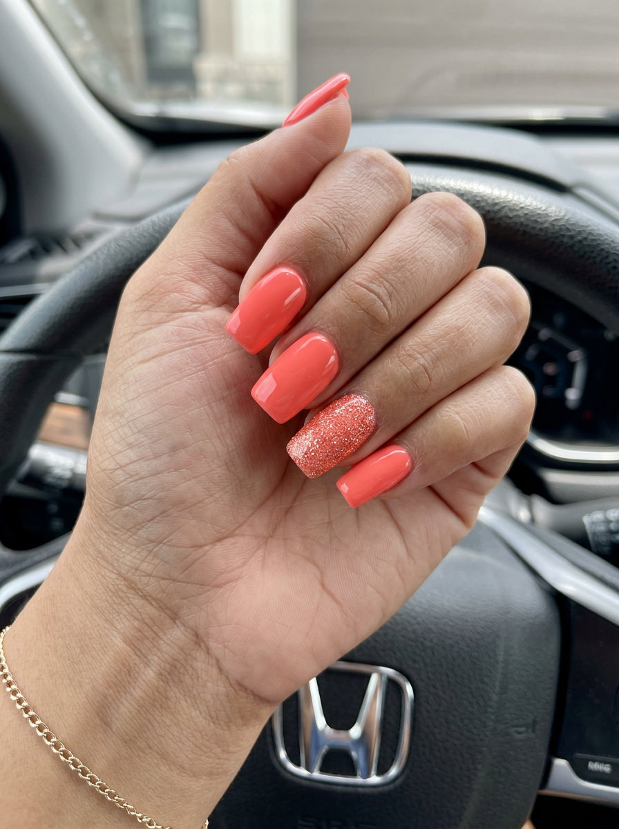 Bright coral square nails with a sparkling coral glitter accent for solid summer nails 2026. Fun for parties.