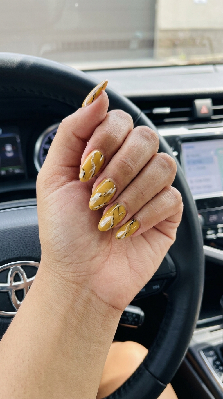 Mustard yellow marble almond nails for summer 2026. Sophisticated and artistic business casual style.
