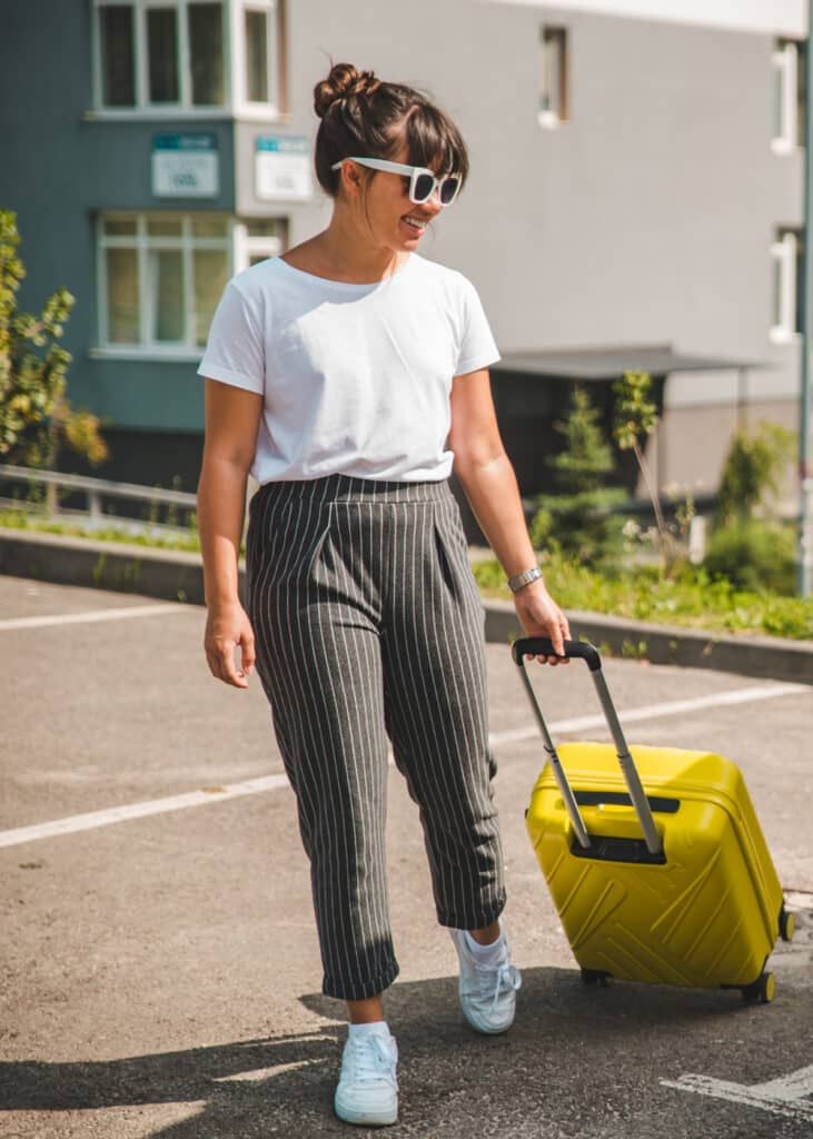 Pinstripe Trousers with White Tee and Yellow Suitcase — Long Flight Outfits
