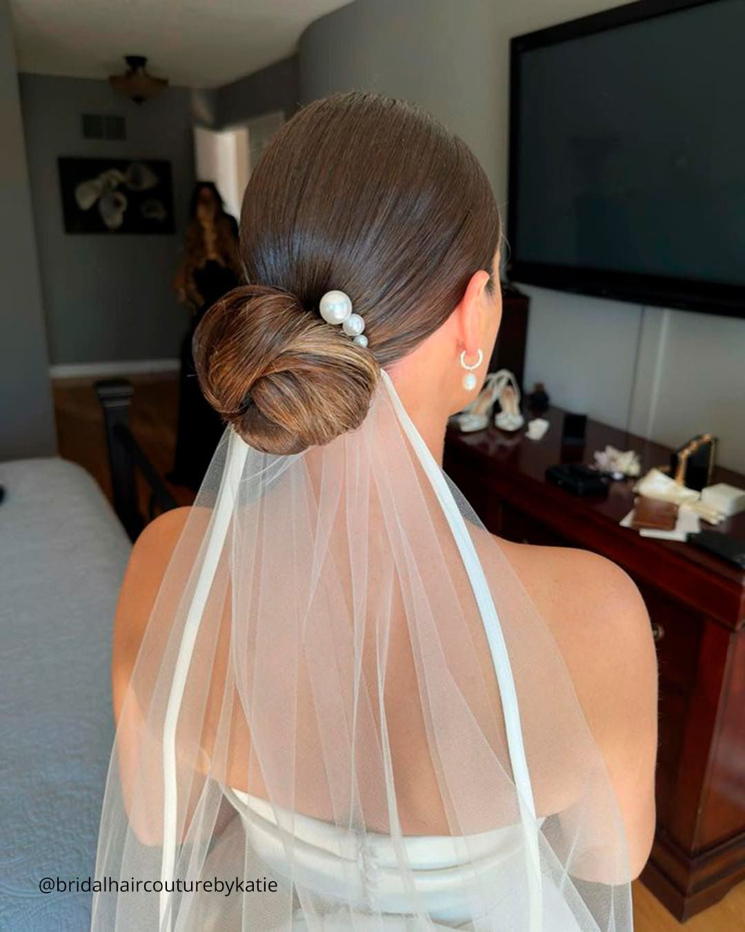Medium Brown Bun With Pearl Accessory and Veil Medium Brown Bun With Pearl Accessory and Veil — Sleek Bun Wedding Hair