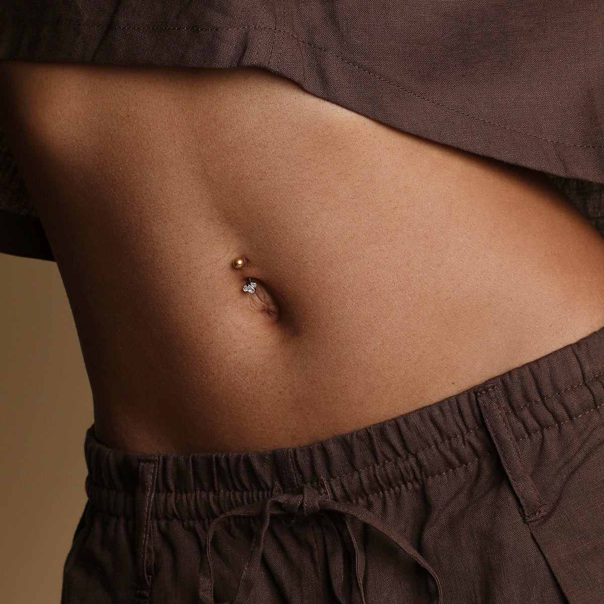 Monochromatic Ease: Gold Belly Ring with Brown Crop Top and Trousers — Belly Button Piercing Ideas