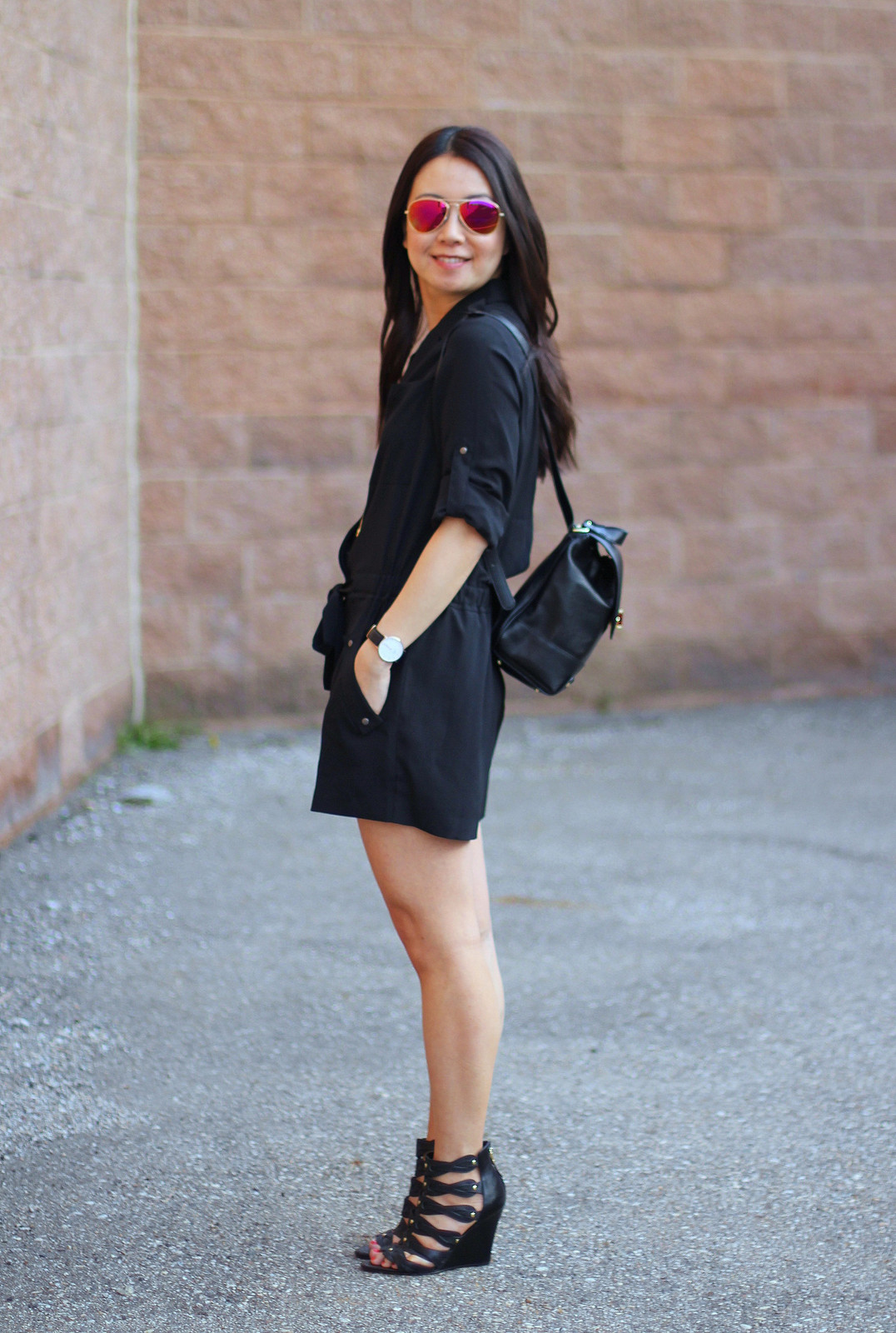 Chic Day Out: Black Romper, Wedge Heels, and a Gold-Hardware Backpack — Backpack Outfits Women