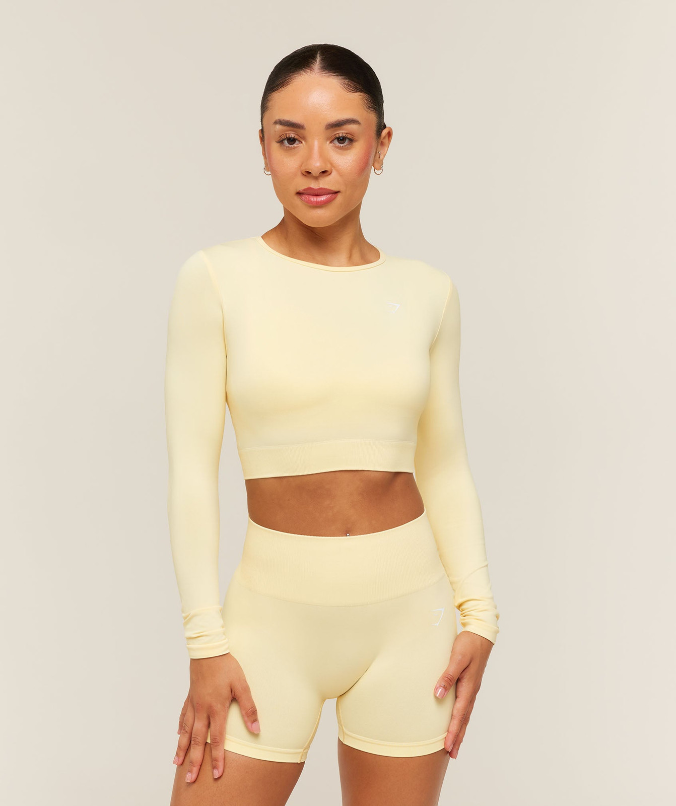 Pale Yellow Long-Sleeve Crop Top and Biker Shorts with Gold Earrings — Gymshark Outfits