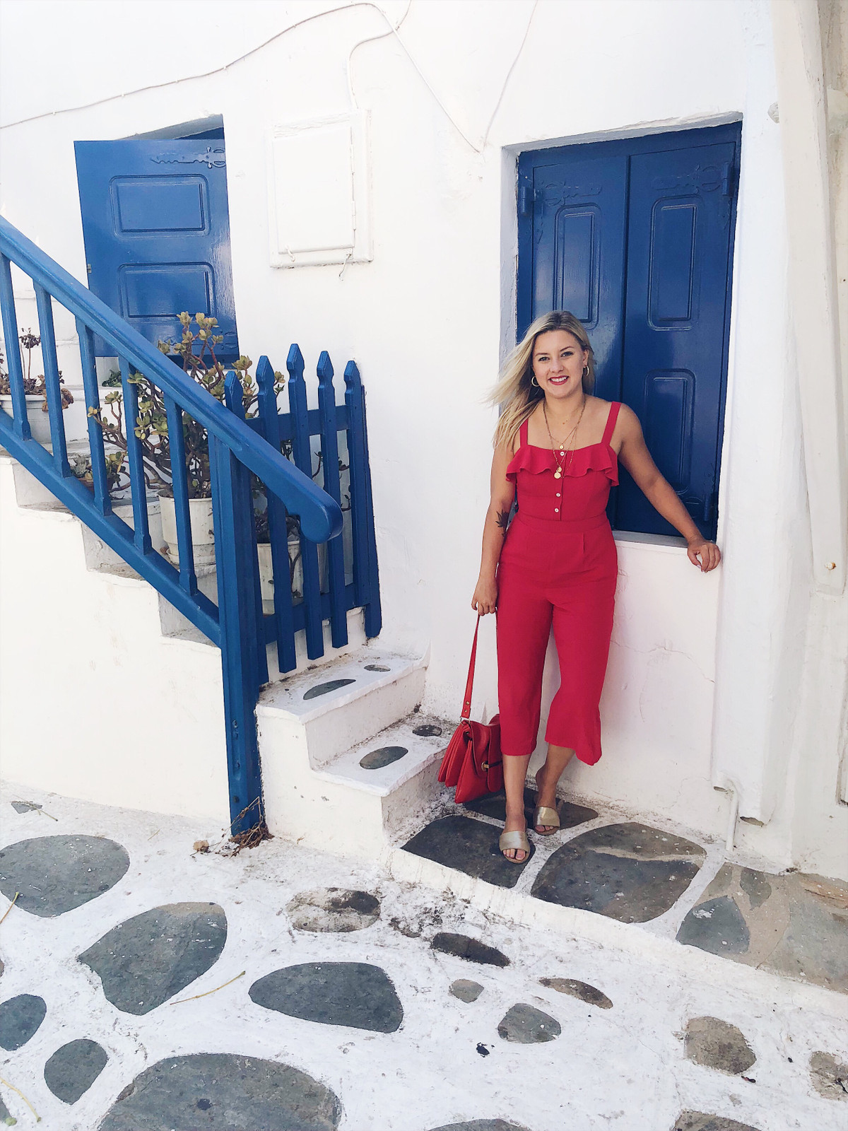 Vibrant Red Jumpsuit Against Greek Architecture Vibrant Red Jumpsuit Against Greek Architecture — Greece Outfits