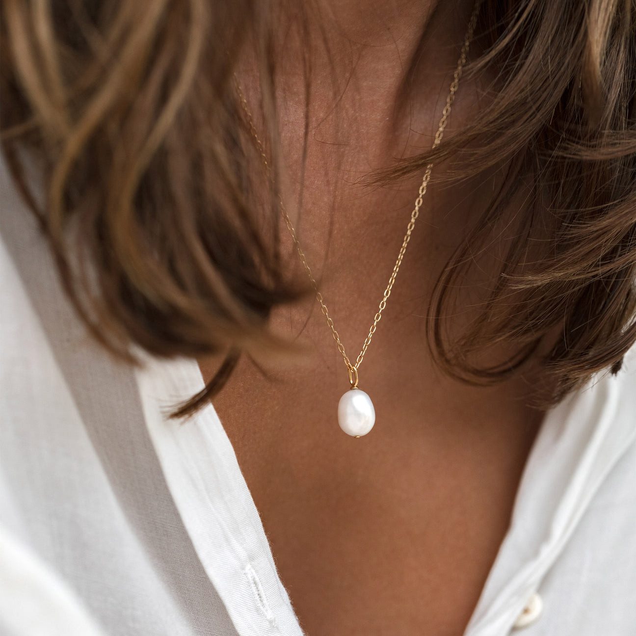 Single Pearl Pendant on Gold Chain with White Collared Shirt Single Pearl Pendant on Gold Chain with White Collared Shirt — Pearl Necklace Outfits