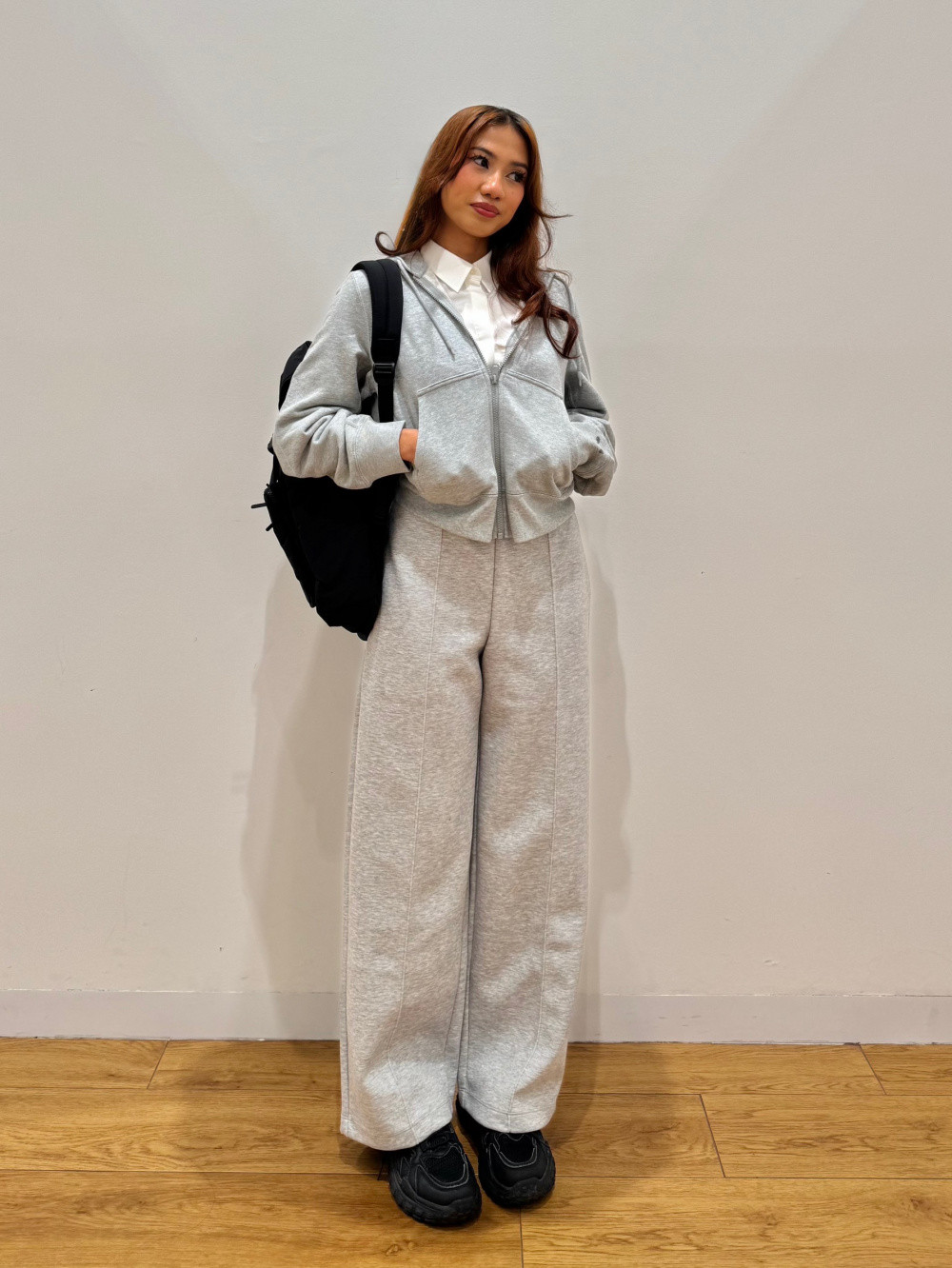 Loungewear Layers: Grey Hoodie, White Shirt, and Wide-Leg Sweatpants with a Black Backpack — Backpack Outfits Women