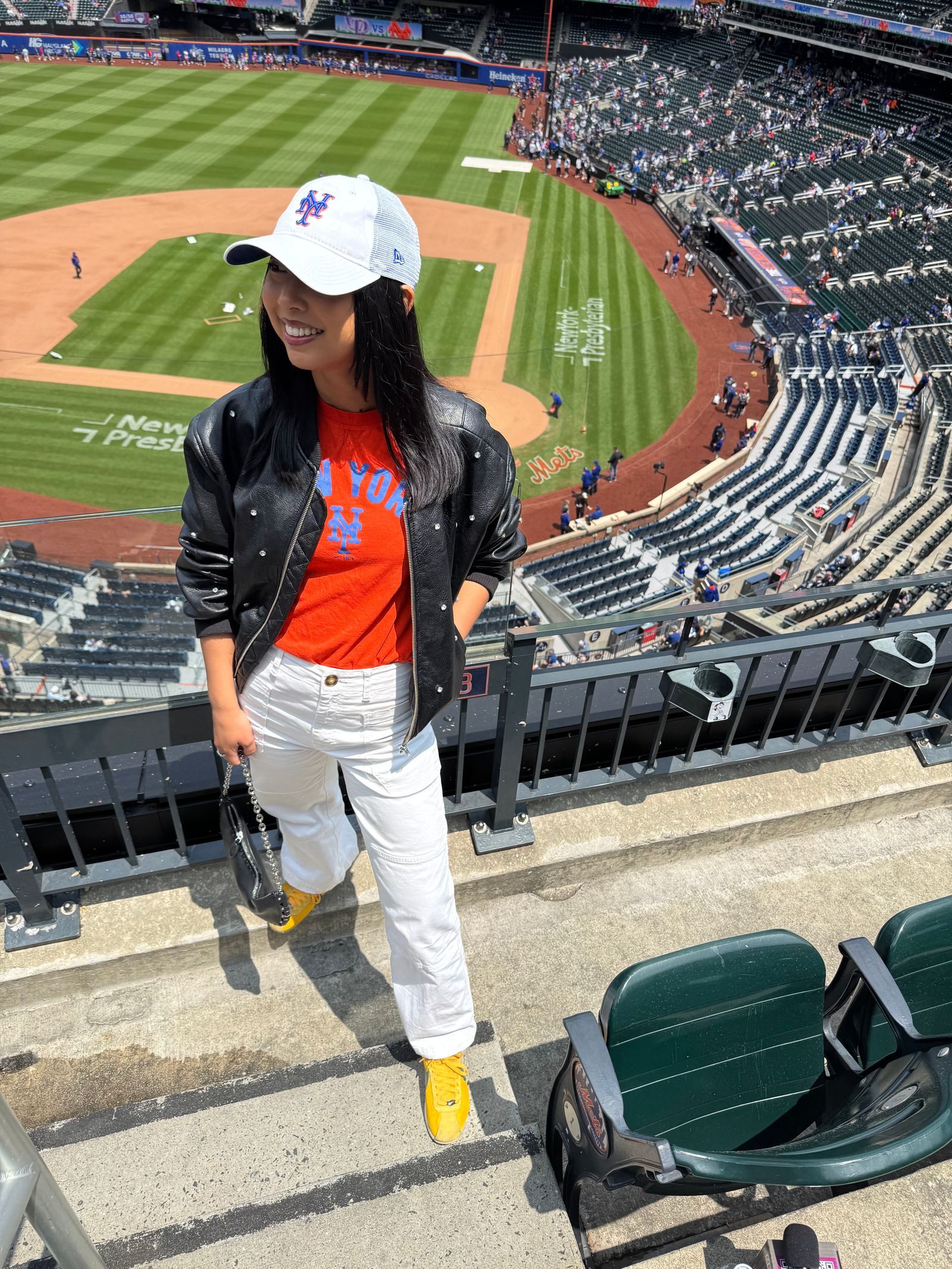 Bomber Jacket Over a Graphic Tee with White Pants — Baseball Game Outfits