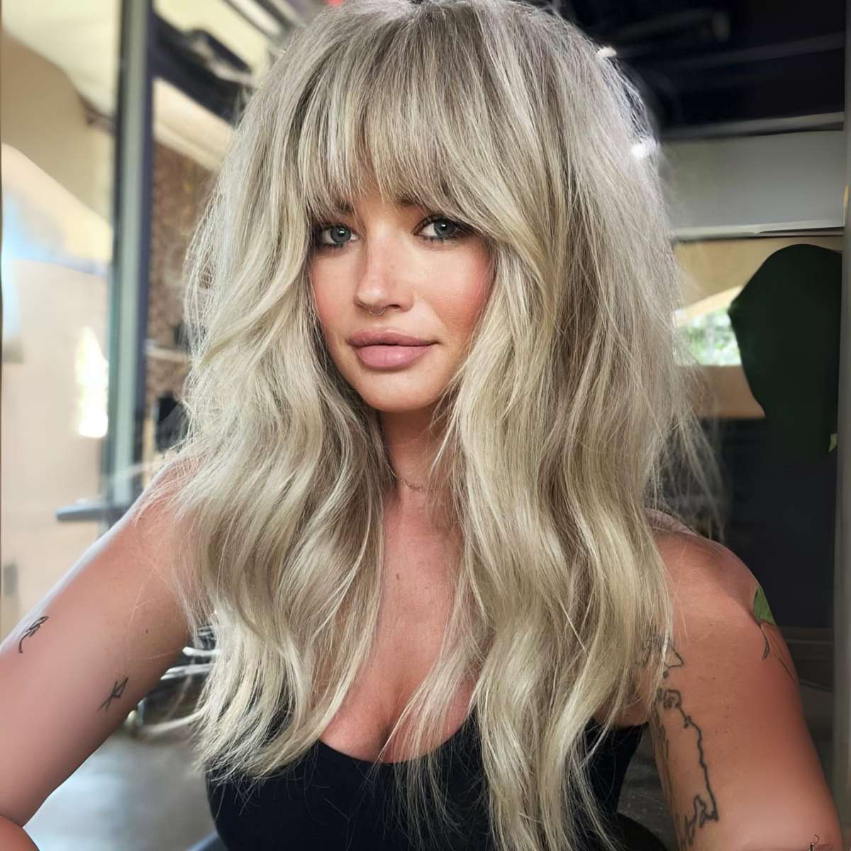 Voluminous Blonde Hair and French Bangs with a Tank Top Voluminous Blonde Hair and French Bangs with a Tank Top
