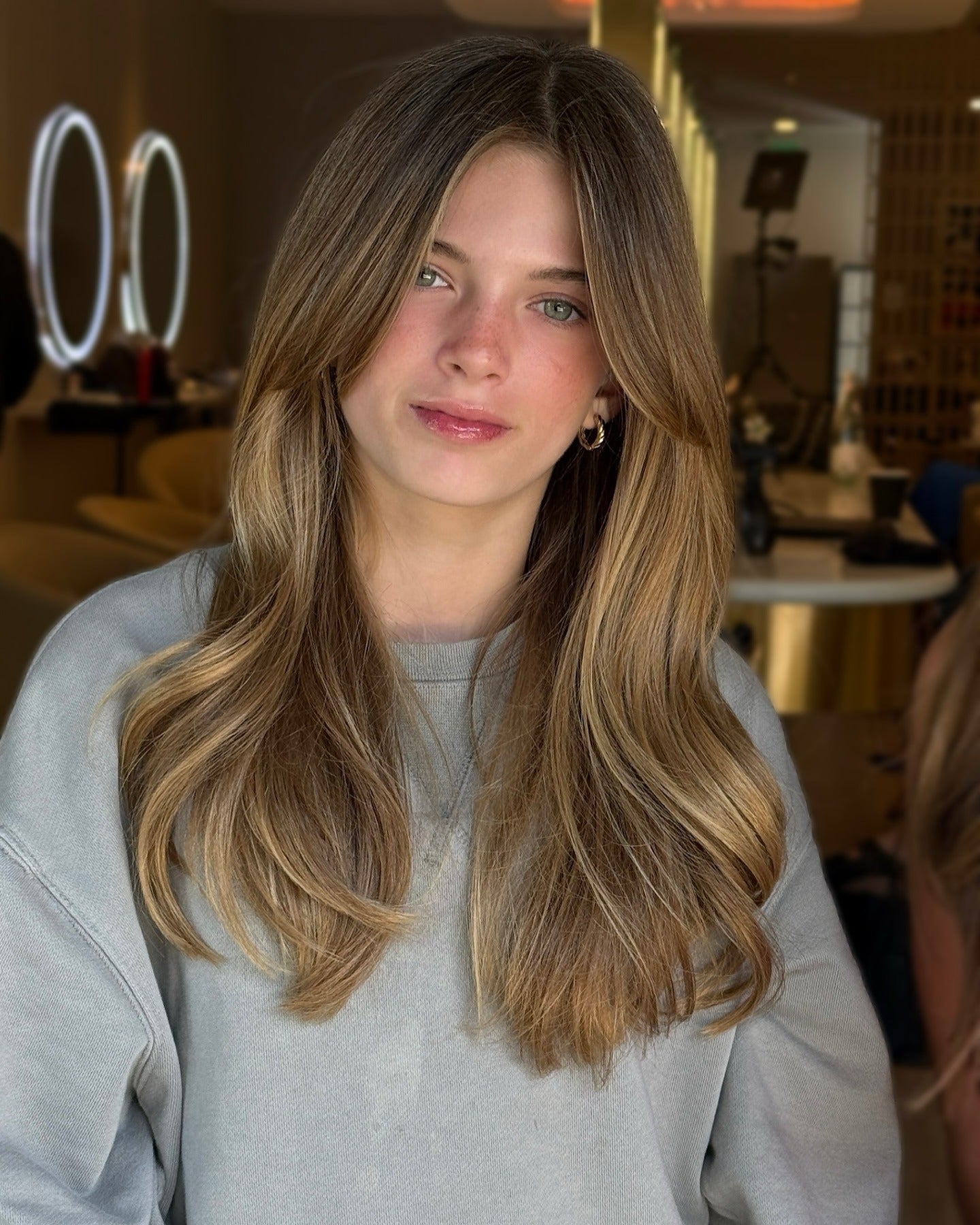 Cozy Casual: Blonde and Brown Hair with Face-Framing Layers and a Grey Sweatshirt — Long Bangs