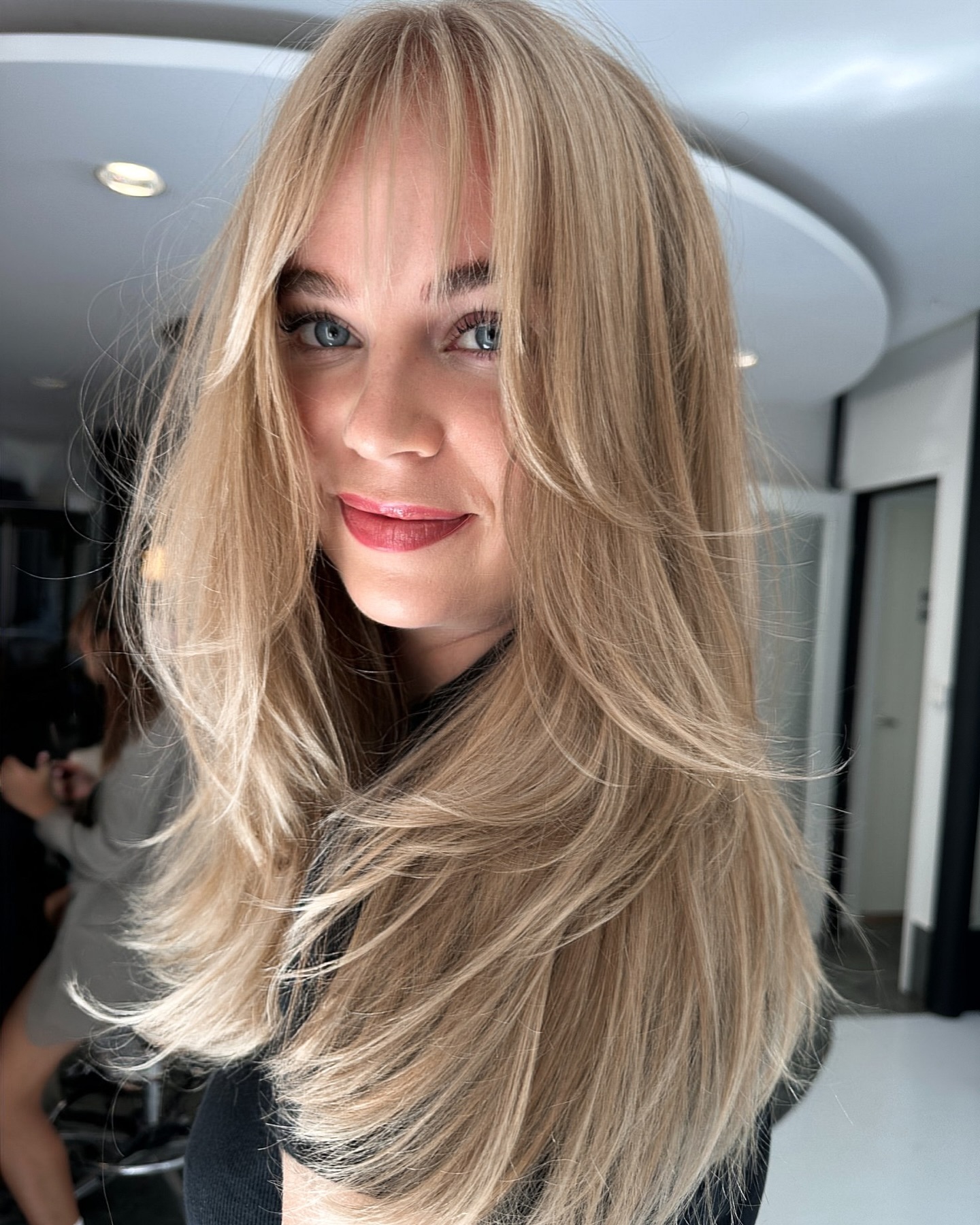 Effortless Style: Blonde Layers with Face-Framing Bangs and a Black Top — Bangs with Layers