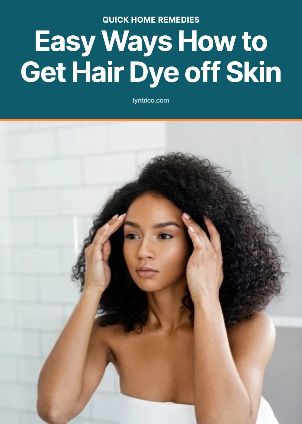 A woman with curly hair touches her temples, looking in a mirror.